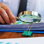 hombre de negocios mirando con lupa documentos