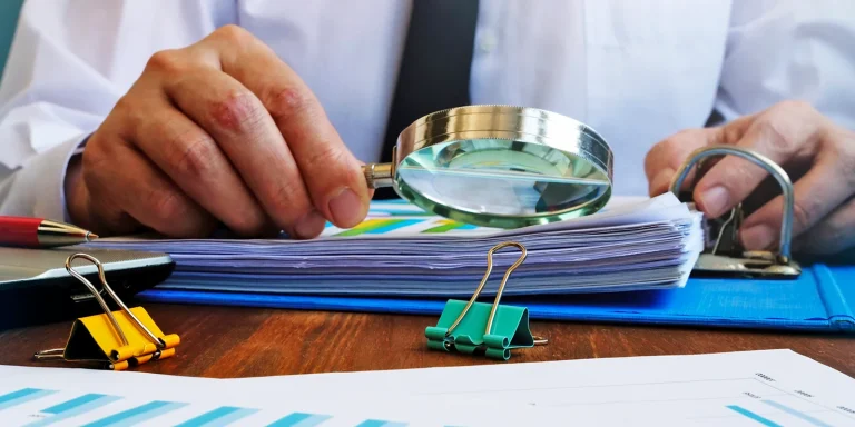 hombre de negocios mirando con lupa documentos