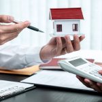 2 hombres sujetando una casa y una calculadora