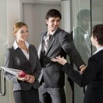 Pareja de agentes inmobiliarios saludando a un compañero