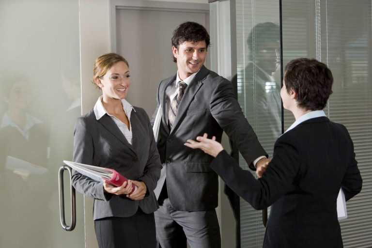 Pareja de agentes inmobiliarios saludando a un compañero