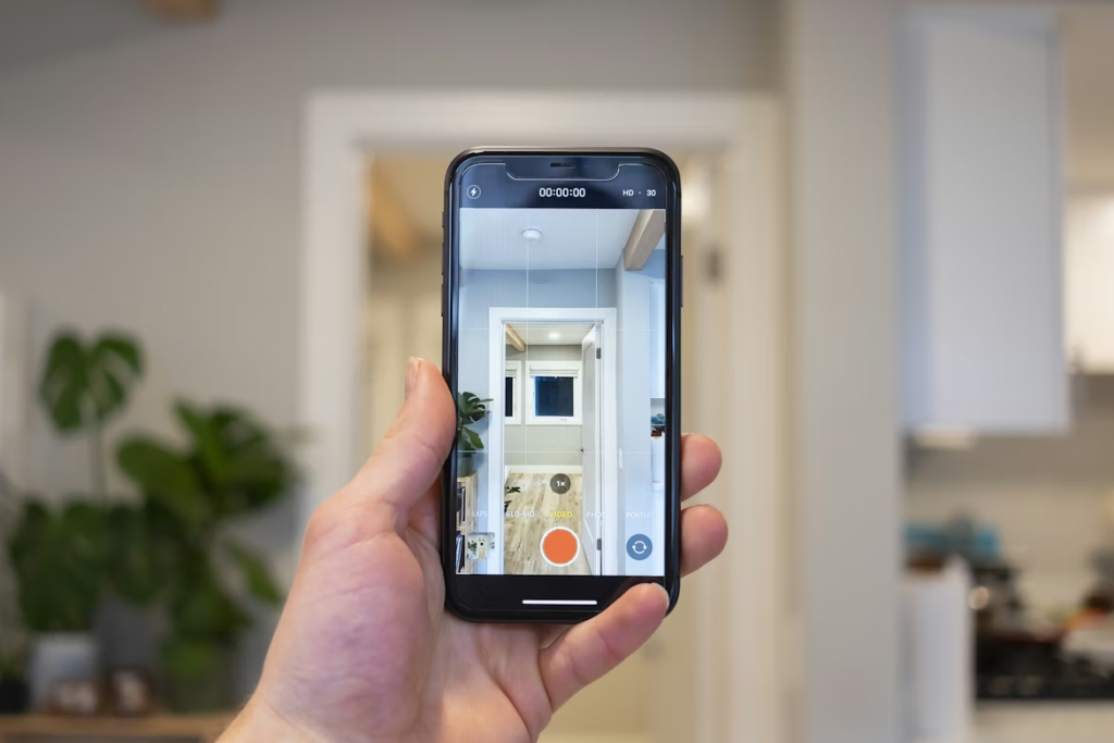 Mano sosteniendo un móvil grabando en vídeo el interior de una vivienda luminosa