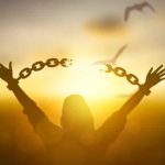 Mujer rompiendo cadenas mirando al atardecer