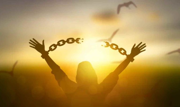 Mujer rompiendo cadenas mirando al atardecer