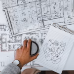 Planos de un arquitecto en una mesa blanca y un café encima de los planos