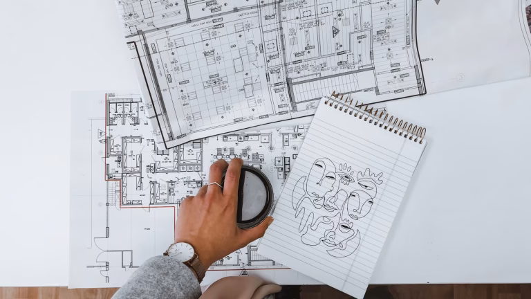 Planos de un arquitecto en una mesa blanca y un café encima de los planos