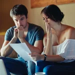 Pareja mirando preocupados impuestos y gastos