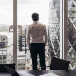 Hombre de negocios mirando pensativo al exterior de una gran ventana